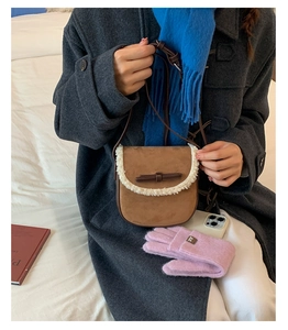 Détail du sac besace en daim marron avec bordure en laine blanche et nœud décoratif