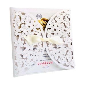 Detail of laser-cut ivory floral lace wedding invitation with a cream ribbon bow