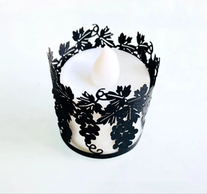 Detail of laser-cut black grape vine pattern paper shade around an LED candle light