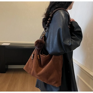 Détail du sac cabas en suède avec bandoulière en perles de bois et pompon doux