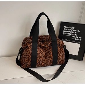 Detailed macro view of large leopard print travel bag with reinforced black strap handles