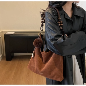 Detail of retro brown faux suede tote bag with wooden bead strap and plush charm