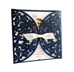 Close-up of navy laser-cut invitation with cream silk ribbon and French insert card