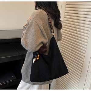 Détail du sac cabas en daim noir avec perles en bois et breloque à pompon vintage
