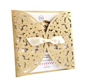 Golden laser-cut butterfly invitation card with white ribbon and elegant floral patterns