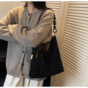 Détail du sac cabas en daim noir avec bandoulière en perles de bois et pompon marron