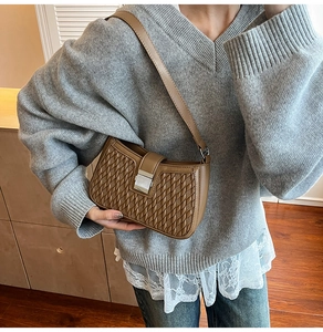 Dettaglio della borsa sottobraccio vintage marrone con trama intrecciata e chiusura in metallo