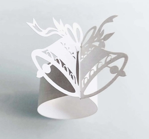 Detail of white bell-shaped paper napkin ring with intricate laser-cut patterns
