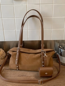 Brown minimalist tote bag with silver studs and mini pouch on a modern background