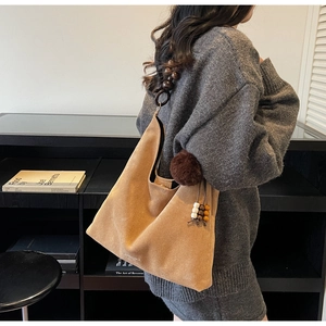 Détail du sac cabas en daim beige avec bandoulière en perles de bois et pompon