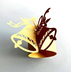 Detail of laser-cut gold Christmas bell napkin ring with intricate hollow bow design