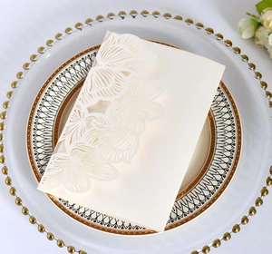 Close-up of laser-cut floral lace wedding invitation on elegant glass dinnerware