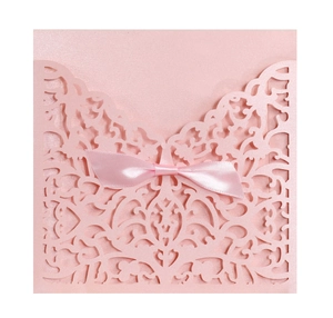 Gros plan d'une invitation de mariage découpée au laser avec nœud élégant en soie rose