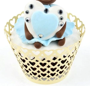 Close-up of golden laser-cut cupcake wrappers with intricate hollow heart patterns