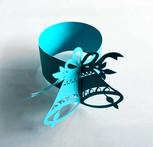 Detail of laser-cut paper napkin ring with Christmas bells and bow in Tiffany blue color