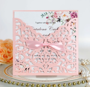 Détail d'invitation rose découpée au laser avec nœud en soie et carte florale