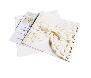 Elegant laser-cut floral wedding invitation with ivory ribbon bow and matching envelope