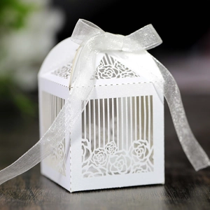 Detailed laser-cut rose pattern on white wedding candy box with a silver ribbon bow