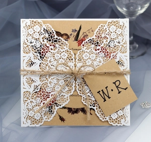 Detail of laser-cut lace invitation with kraft paper, twine, and rustic floral illustration