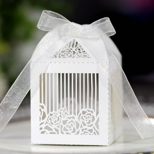 Detailed laser-cut white hollow wedding favor box with rose patterns and ribbon bow