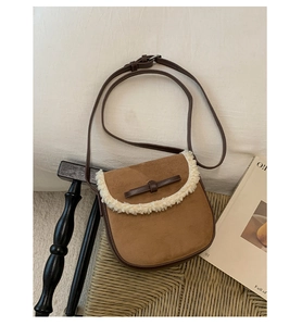 Détail du sac besace en daim marron avec bordure en fausse fourrure et fermoir