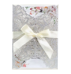 Laser-cut silver glitter wedding invitation card with ribbon and floral insert detail