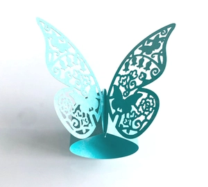 Detail of laser-cut butterfly napkin ring in turquoise with intricate floral wing patterns