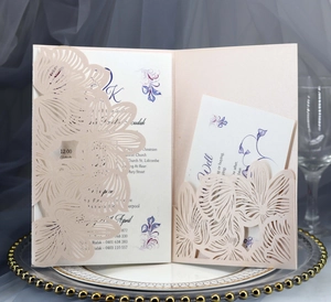 Close-up of laser-cut pearl pink wedding invitation with intricate floral hollow pattern