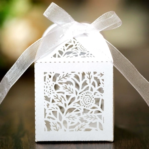 Close-up of white laser-cut hollow paper gift box with ribbon for wedding favors