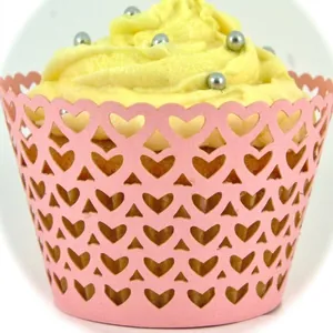Pink laser-cut cupcake wrappers with hollow heart patterns for festive baking decoration