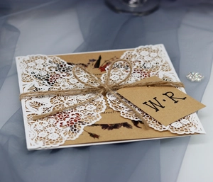 Close-up of laser cut lace wedding invitation with kraft paper card and jute twine