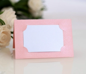 Détail du marque-place de mariage rose pailleté avec insert blanc et décor floral