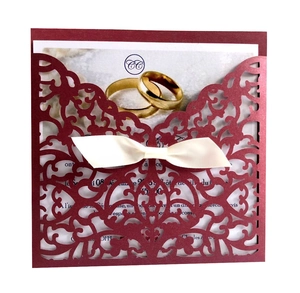 Détail de l'invitation découpée au laser bordeaux avec nœud ivoire et motif bagues