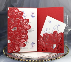 Detail of laser-cut red floral wedding invitation with white cards on a tray