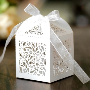 Close-up of laser-cut hollow rose wedding favor box with white organza ribbon bow