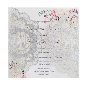 Macro shot of laser-cut silver glitter wedding invitation with floral insert card