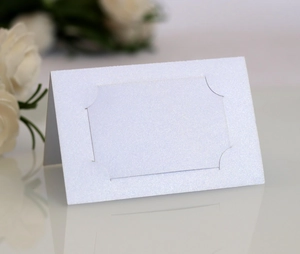 Gros plan d'un marque-place de mariage en nacre blanche avec cadre découpé au laser et fleurs