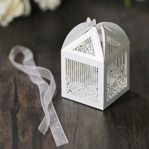 Detail of white laser-cut hollow rose candy box with elegant ribbon on wood surface