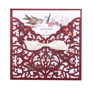 Détail de l'invitation de mariage bordeaux découpée au laser avec nœud en satin beige