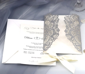 Close-up of laser cut silver glitter invitation with a silk ribbon and floral details