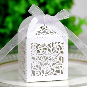 Macro shot of white laser-cut hollow rose favor box with a purple ribbon bow on white plate