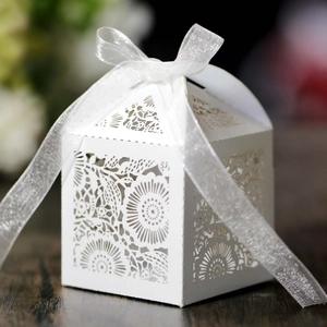 Détail de boîte à bonbons blanche découpée au laser avec motifs floraux et ruban argenté