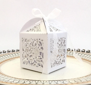 Detail of white laser-cut hollow rose wedding favor box with a satin ribbon bow