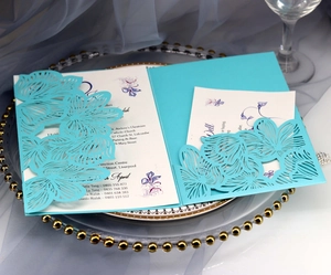 Detail of teal blue laser-cut lace wedding invitation with intricate floral patterns