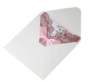 Detailed laser-cut glitter pink wedding invitation with white envelope and pink satin bow