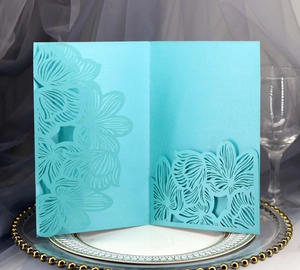 Detail of light blue laser-cut wedding invitation with intricate lace floral patterns