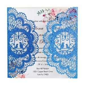 Close-up of glittery blue laser-cut wedding invitation with elegant floral inner page