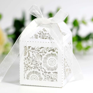 Détail d'une boîte à dragées blanche découpée au laser avec motifs floraux et nœud en ruban