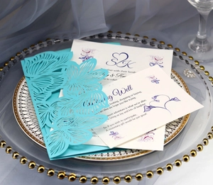 Detailed macro view of laser-cut turquoise wedding invitation suite on elegant glass tray
