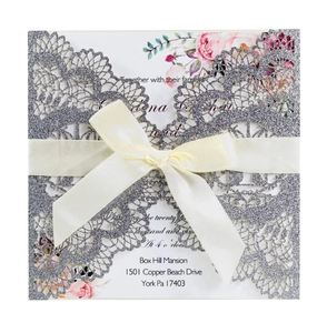 Detailed laser-cut silver glitter wedding invitation cover with elegant silk ribbon bow
